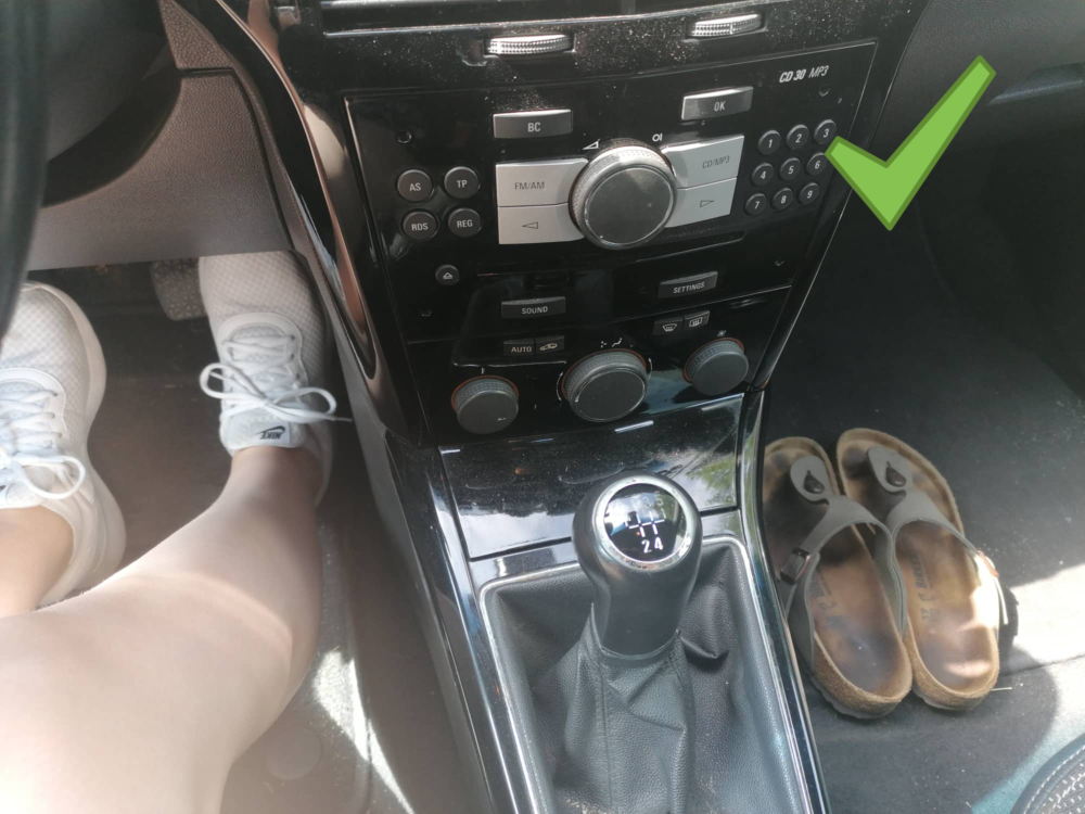 車の運転席と助手席の足もとが写っている写真です。助手席には、サンダルが脱いで置いてあります。ドライバーはスニーカーを履いています。