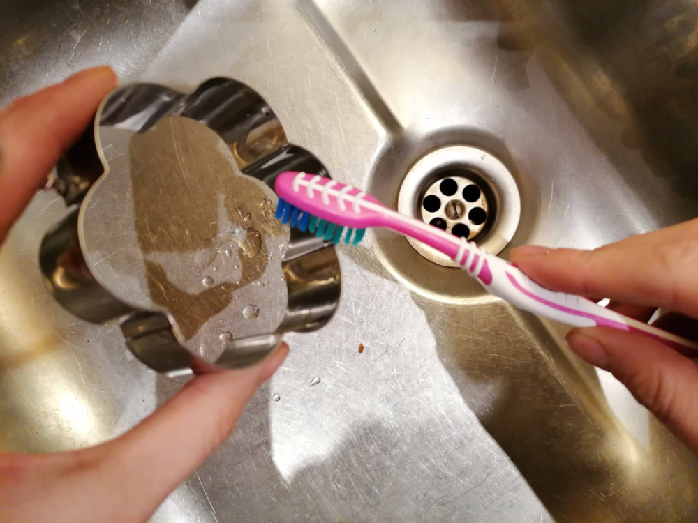 Ausstechformen reinigen: Mithilfe einer Zahnbürste kannst du Teigreste aus jeder noch so kleinen Ecke der Plätzchenform entfernen.